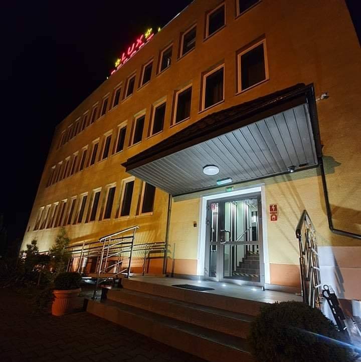 Budynek LUX RESORT nocą, podświetlony neon z nazwą nad wejściem