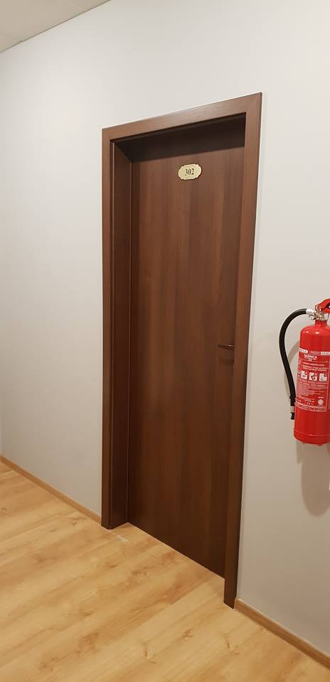 Drzwi pokoju numer 302 na korytarzu, obok gaśnica